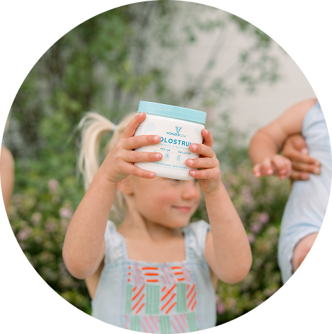 Child holding WonderCow Colostrum Powder outdoors